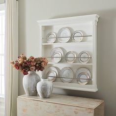 two vases with flowers sit on a dresser