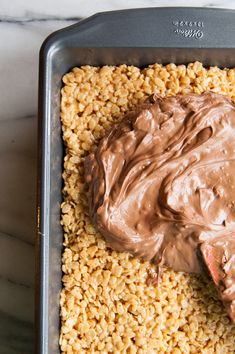 a pan filled with chocolate frosting on top of oatmeal