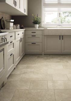 a kitchen with white cabinets and tile flooring