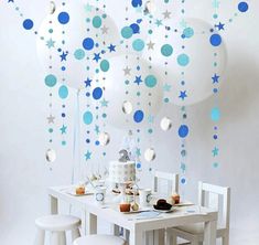 blue and white balloons are hanging from the ceiling above a table with desserts on it