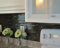 three vases filled with flowers sitting on top of a counter next to a microwave