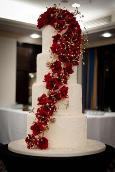 a white wedding cake with red flowers on it