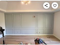 an empty room with hard wood flooring and walls painted white, has a fan in the corner