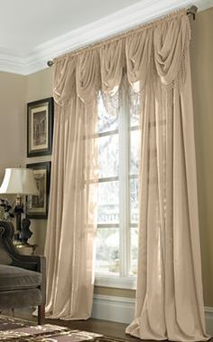 a living room filled with furniture and a large window covered in draping next to a couch