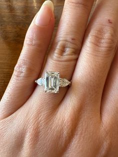 a woman's hand with a ring on it and an emerald stone in the middle