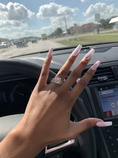 a woman's hand on the steering wheel of a car with her nails painted white