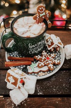 a cup filled with hot chocolate covered in marshmallows and gingerbread cookies