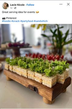 a wooden tray filled with food on top of a white table next to a potted plant