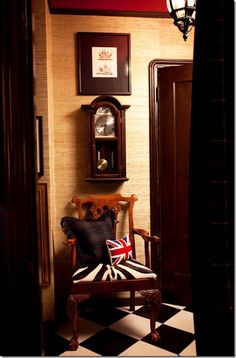 a chair sitting in front of a clock on a wall next to a doorway with a checkered floor