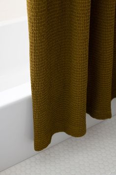 a close up of a shower curtain next to a bathtub with white tiles on the floor