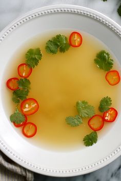 a white plate topped with sliced tomatoes and green garnish next to cilantro