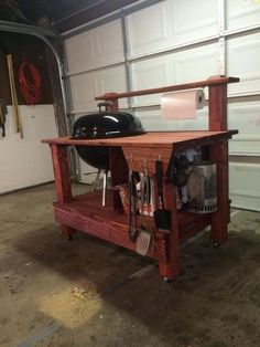 an outdoor bbq table with grilling tools and utensils on it in front of a garage door