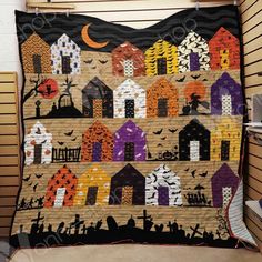 a quilt is hanging on the wall in front of a window with bats and houses