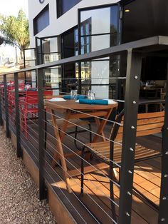 a wooden table sitting on top of a metal rail next to a tall white building