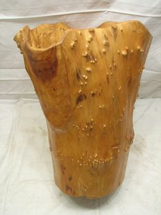 a large wooden vase sitting on top of a white sheet covered tablecloth with holes in it