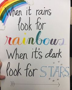 someone holding up a sign that says when it rains look for rainbows, when it's dark look for stars