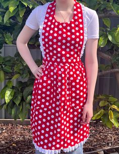 a woman wearing a red and white polka dot apron with her hands on her hips