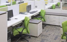 an office cubicle with lime green chairs and white desks