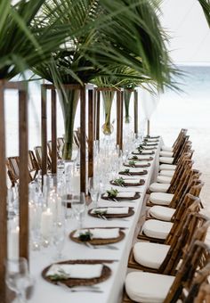 a long table set up with place settings and palm trees