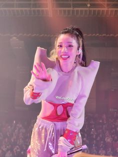 a woman standing on top of a stage with her hands in the air and smiling