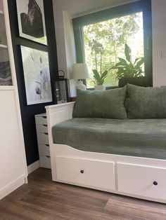 a day bed with storage underneath it in a room that has wood floors and black walls