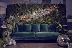 a couch sitting in front of a green wall covered with plants and disco balls on the floor