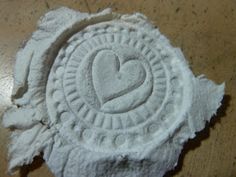 a heart carved into the side of a piece of paper on a table with writing underneath it