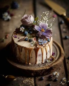 a cake decorated with flowers and icing sitting on a wooden table next to a knife