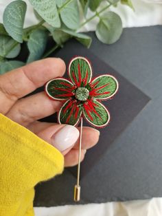 a person holding a pin with a flower on it