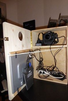 an open wooden box with cords and cameras in it on top of a black table