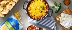 a casserole dish with cheese, salsa and tortilla chips on the side