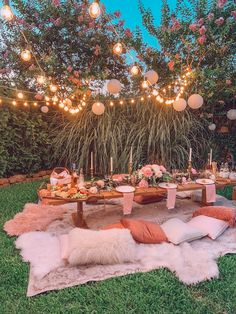 an outdoor dinner setting with lights strung over the table and pillows on the rugs