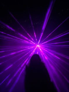 a person standing in front of purple laser lights