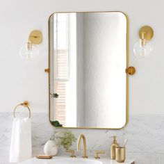 a bathroom with marble counter tops and gold fixtures on the wall, along with a large mirror