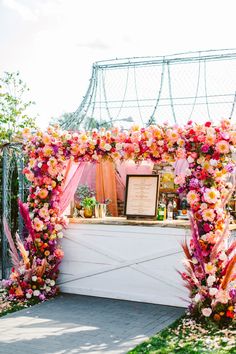 an outdoor ceremony with flowers and greenery on the side wall, along with a menu