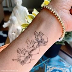 a woman's arm with a tattoo on it and flowers in the back ground