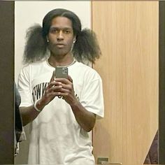 a man taking a selfie in front of a mirror with his hair blowing out