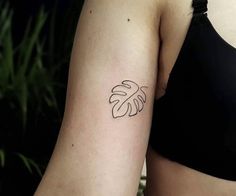 a woman's arm with a leaf tattoo on the left side of her right arm