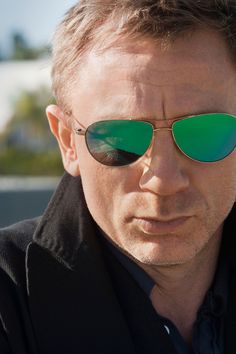 a man wearing green mirrored sunglasses looking off to the side