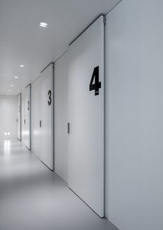 an image of a hallway with white walls and black numbers on the door to each room