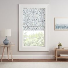 a living room with white walls and a window covered in floral roman blind coverings