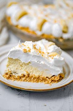 a slice of lemon meringue pie on a plate with the rest of the pie in the background