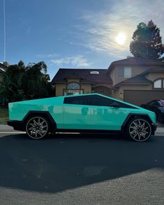 a blue sports car parked in front of a house with the sun shining on it