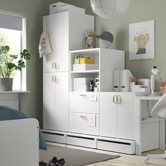 a bedroom with green walls and white furniture in the room, including a bookcase