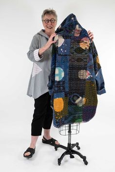 an older woman is holding up a jacket made out of old clothes and buttons on a mannequin