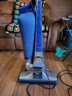 a blue and silver vacuum sitting on top of a hard wood floor