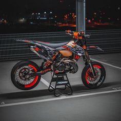 an orange and black dirt bike parked in a parking lot