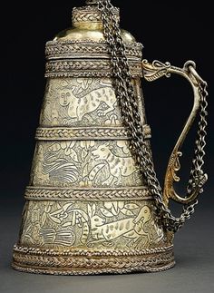 an ornately decorated brass teapot with chains