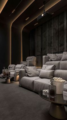 a room filled with lots of grey couches and chairs next to a wall mounted movie projector