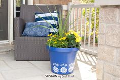 a blue flower pot sitting on top of a patio next to a chair and pillows